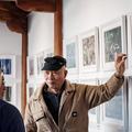 Persoon geeft uitleg aan een kleine groep in een ruimte met ingelijste foto's aan de muur.
