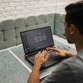 Persoon werkt op een laptop met een digitale interface op het scherm.